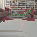 A packaged meringue bar in a red and white wrapper labeled 'Flower & White' and 'Chocolate Dipped Strawberry', placed on a white surface with a blurred store shelf background video
