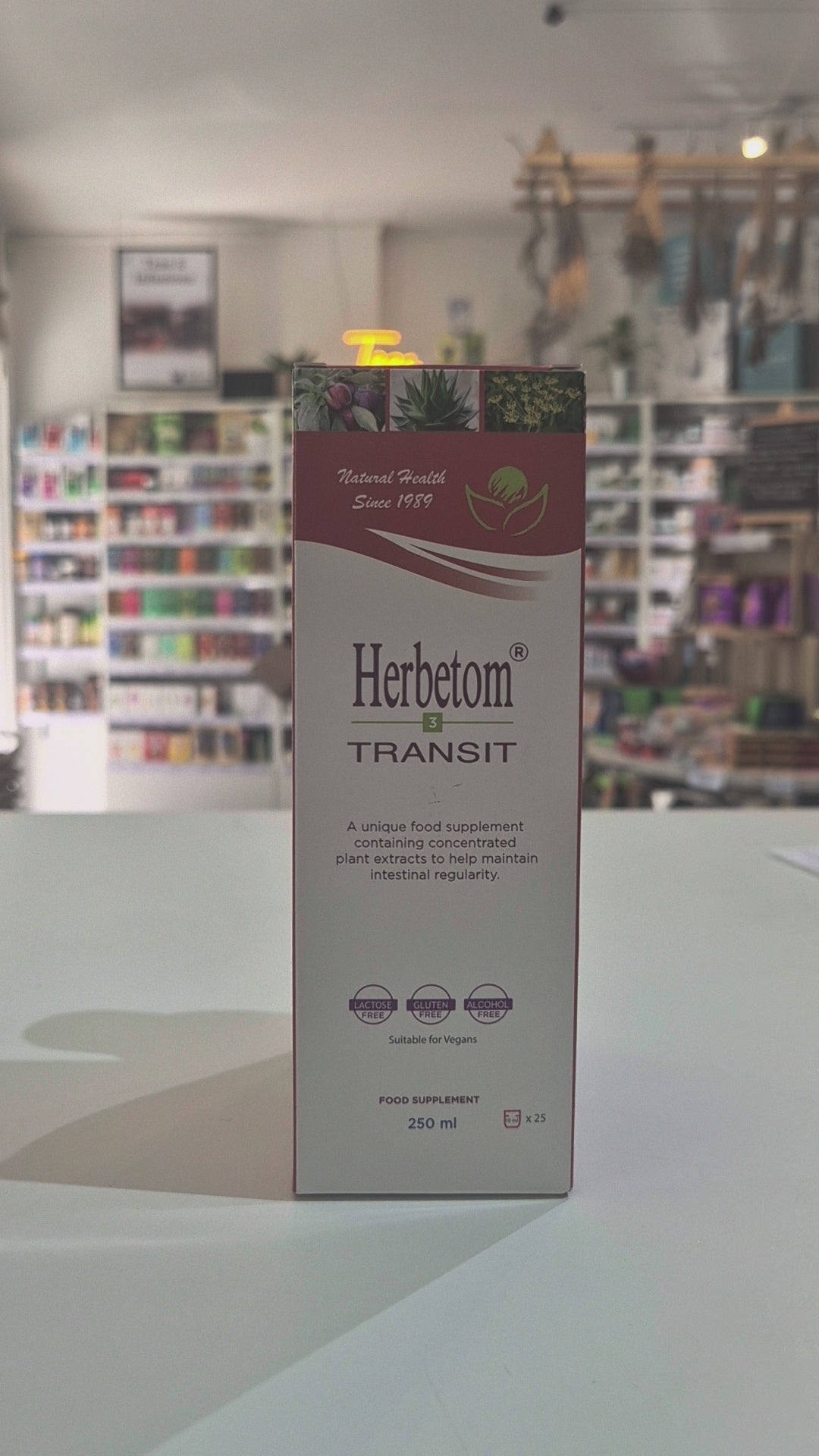 A bottle of Herbetom Transit herbal supplement and its matching cardboard box, displayed on a white shelf in a blurred retail store setting video
