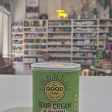 Can of 'Sour Cream & Onion' potato crisps from The Good Crisp Company on a white surface with a blurred store background.