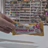 A packaged meringue bar snack placed on a white counter in a blurred shop interior with shelves and hanging decor in the background video