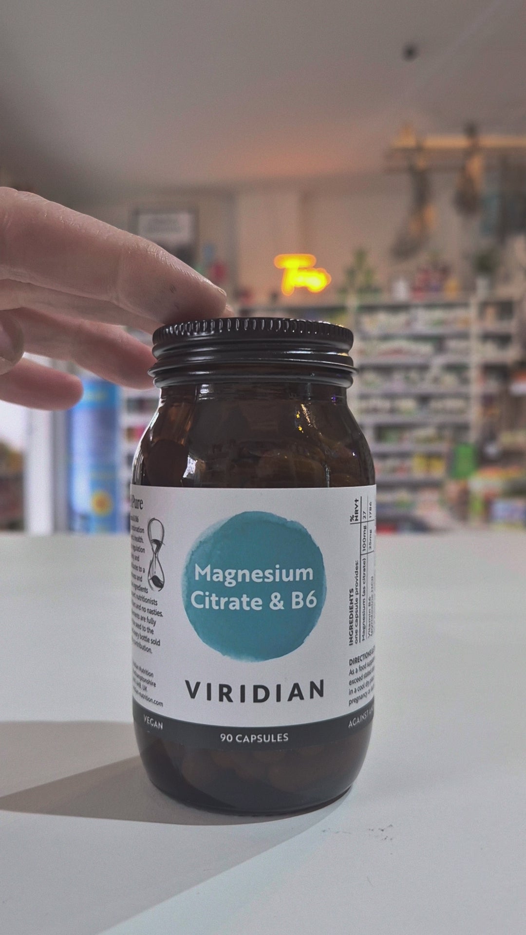 Bottle of Viridian Magnesium Citrate & B6 supplement on a white surface with a blurred store background.