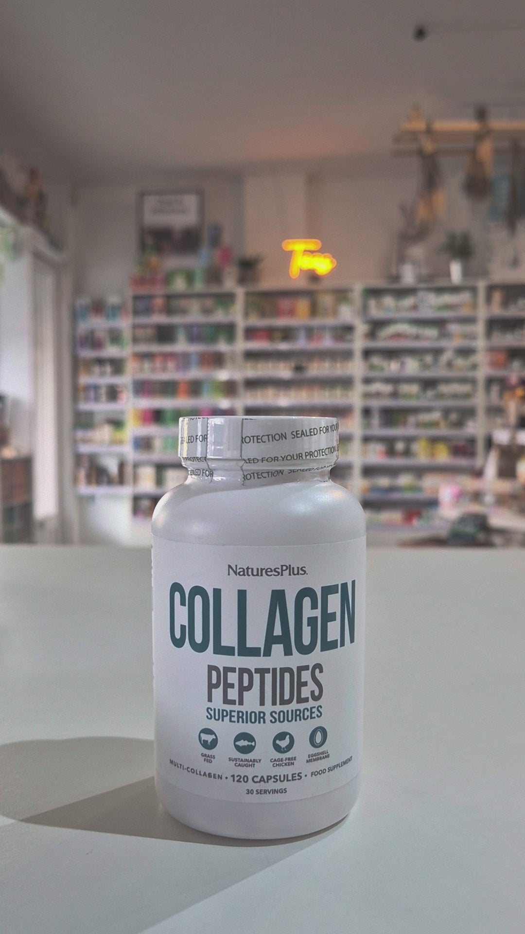 A bottle of Nature's Plus Collagen Capsules, labeled 'Collagen Peptides', indicating 120 capsules in the container. Collagen peptides supplement bottle on a table with a store interior in the background video