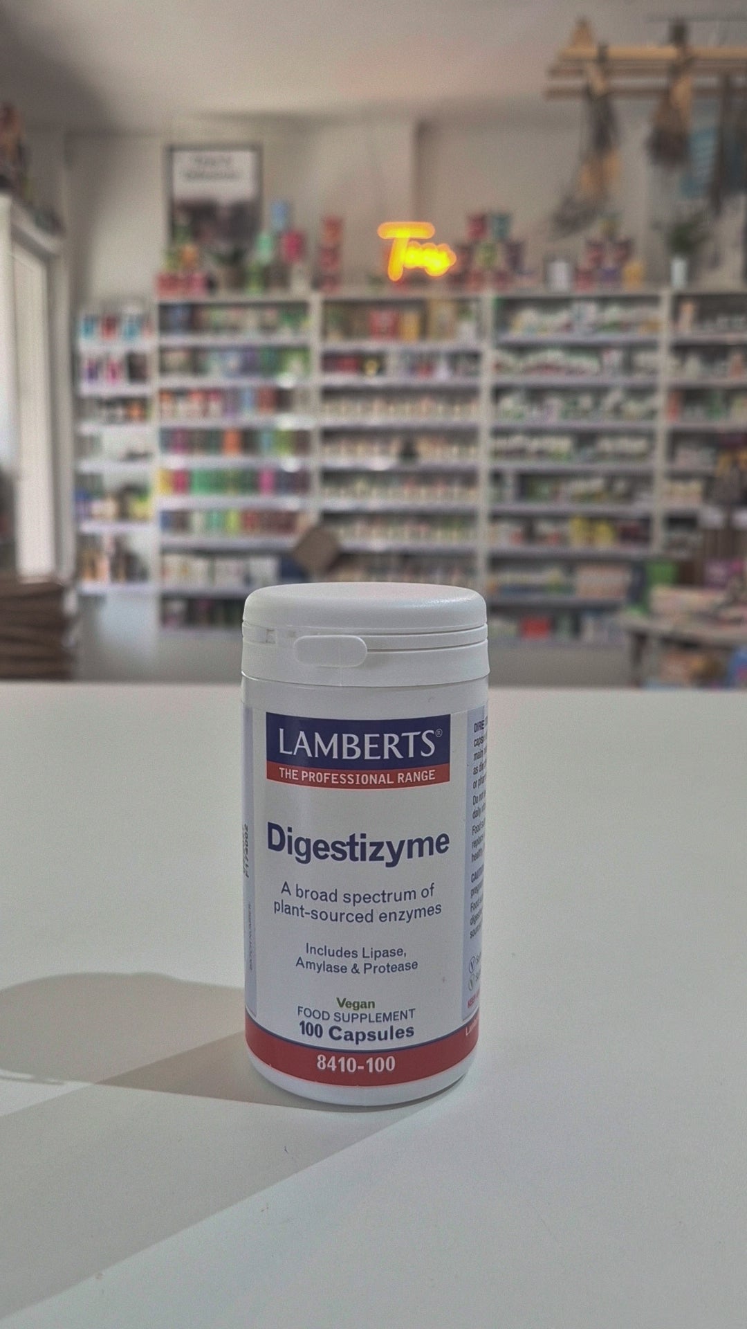 Lamberts Digestizyme supplement container on a white surface with a blurred background