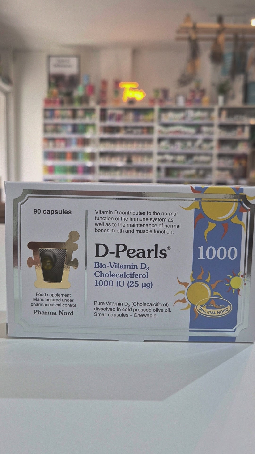 Box of D-Pearls 1000 capsules with a blurred bookstore background