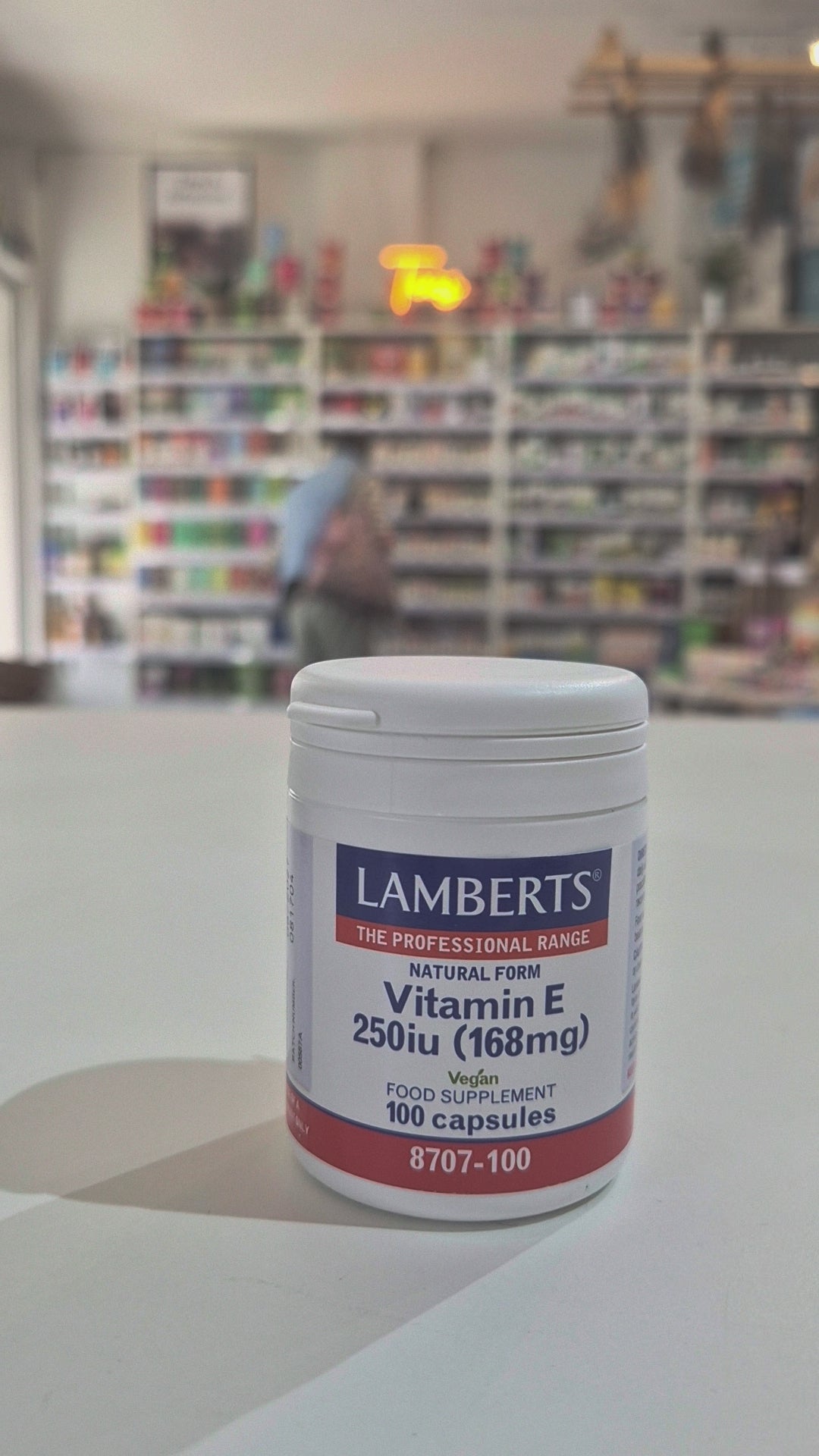 Lamberts Vitamin E supplement container on a table with a blurred background