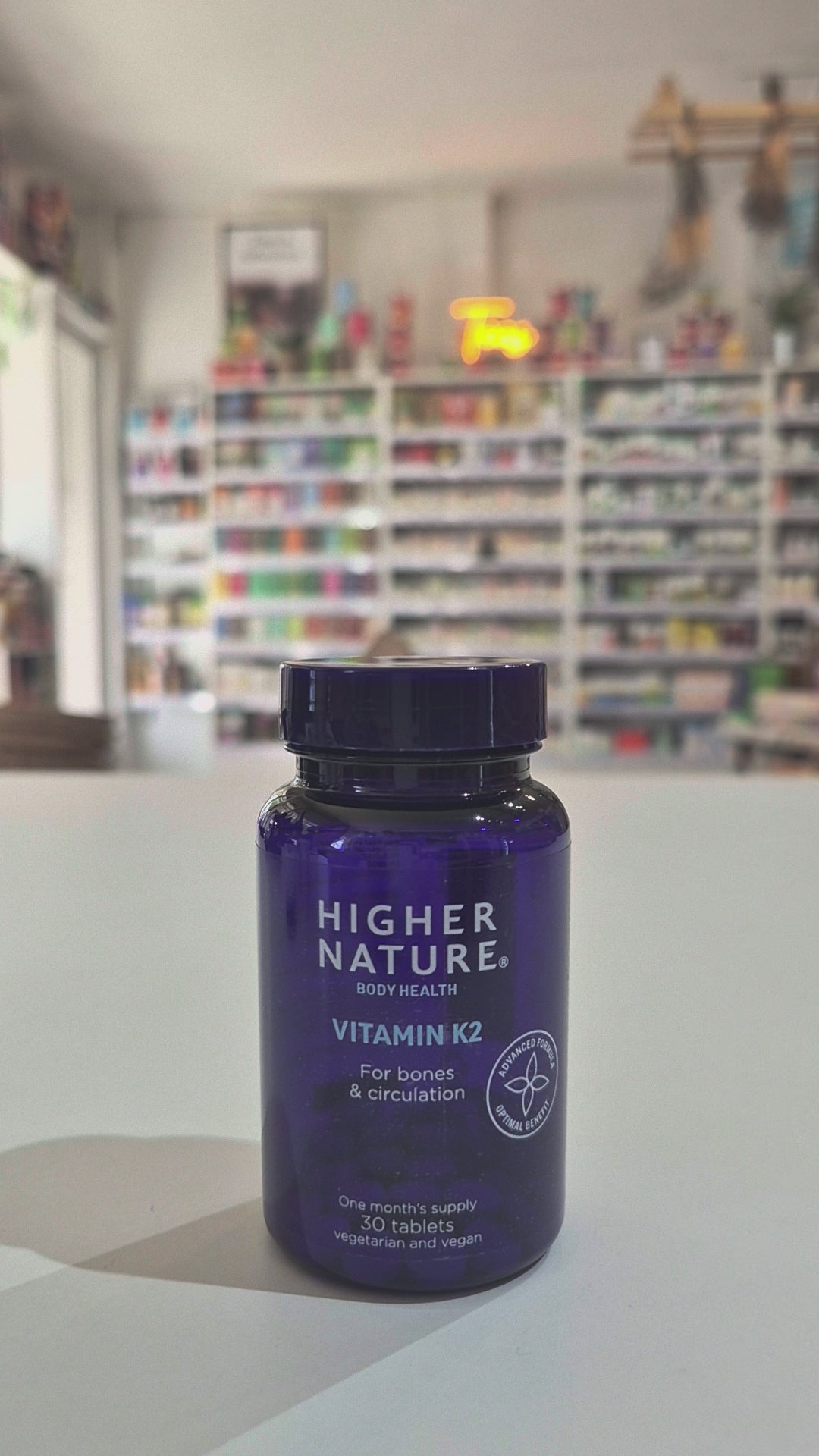 Blue bottle of Higher Nature Vitamin K2 on a light surface with a blurred background