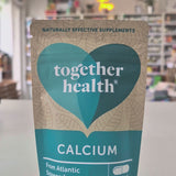 Packaging of Together Health Calcium supplements with a clear window showing the tablets inside. The package is predominantly blue and white with a heart shape design in a shop setting video. 