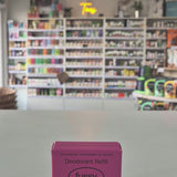 Pink deodorant refill box labeled 'fussy' on a gray surface with a blurred store background.