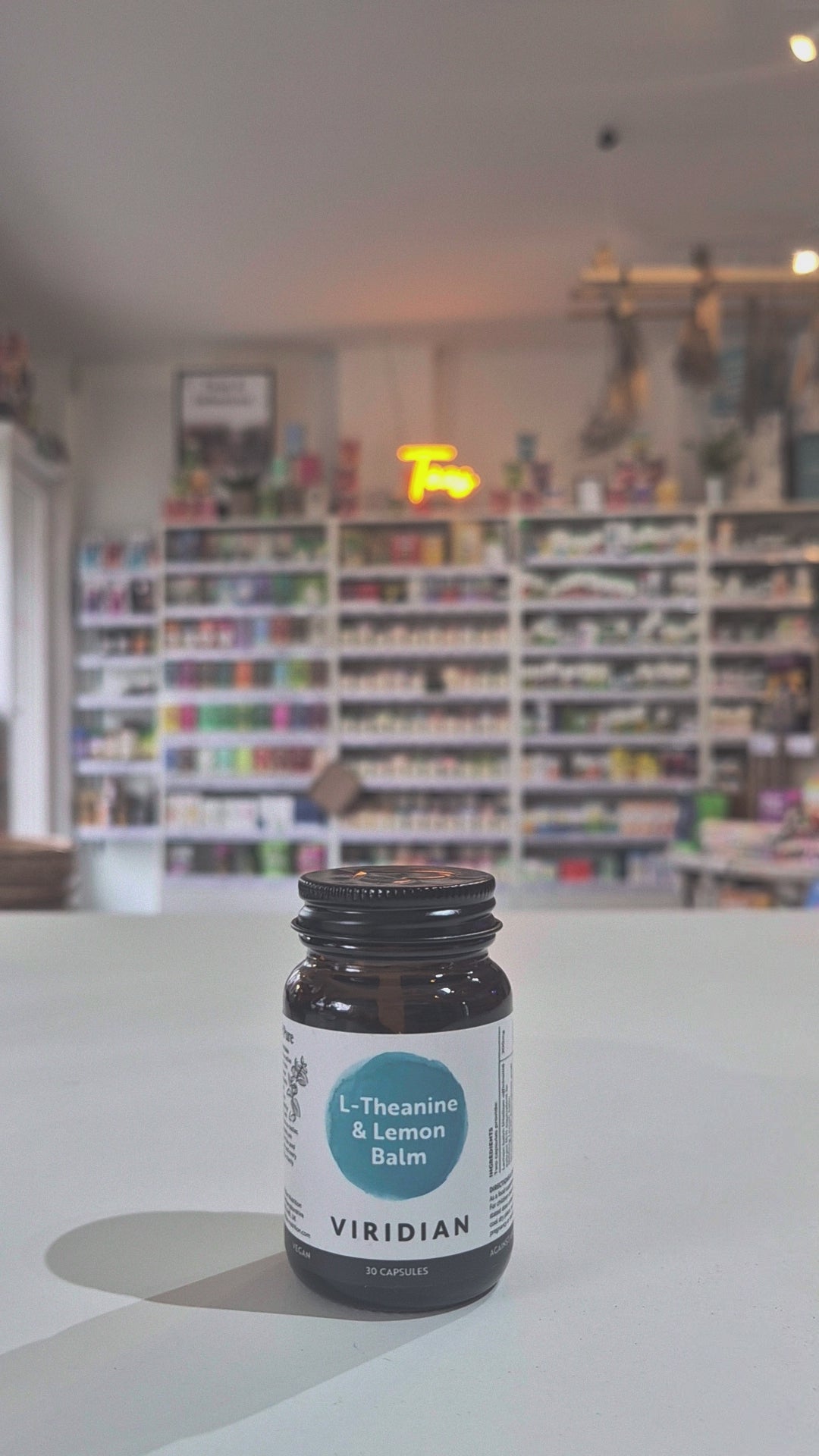 A bottle of Viridian Nutrition L-Theanine & Lemon Balm supplement, with 30 capsules inside, labeled with the product name and strength of 500mg.