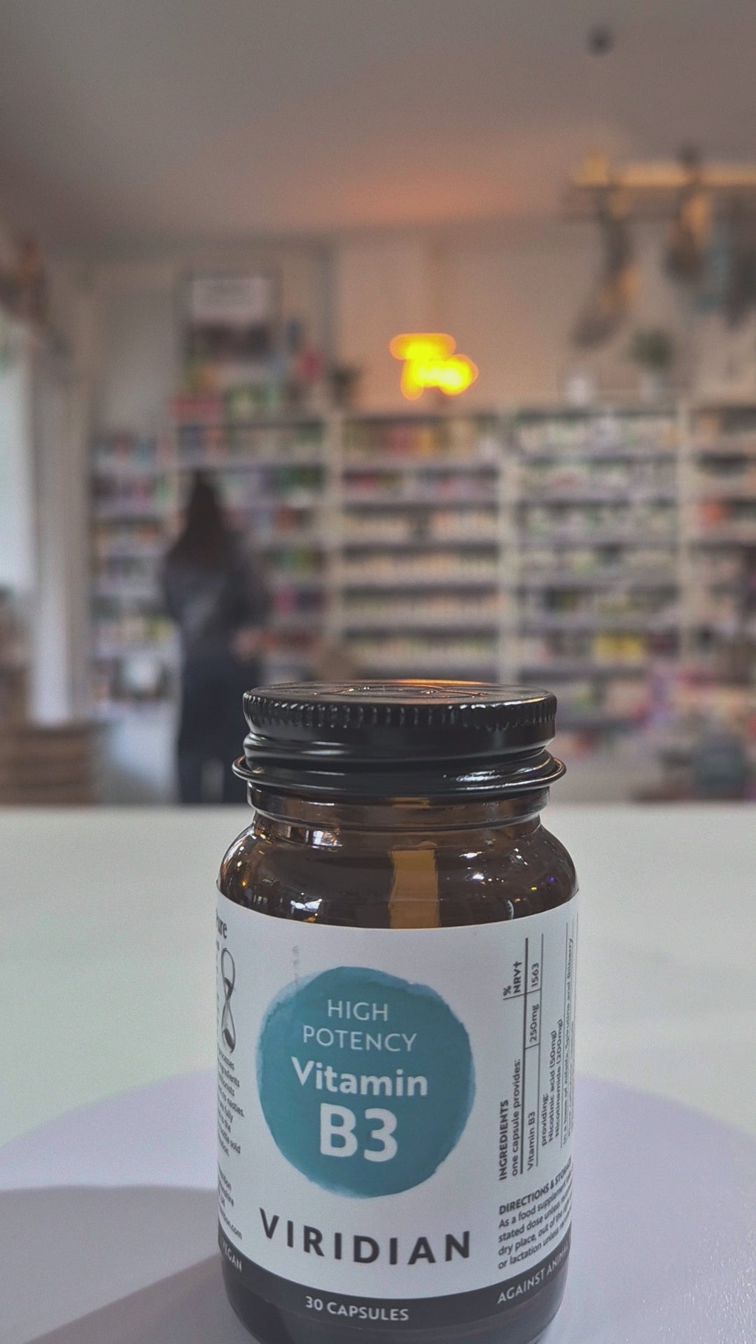 Vitamin B3 supplement bottle with 'Viridian' label on a blurred store background.