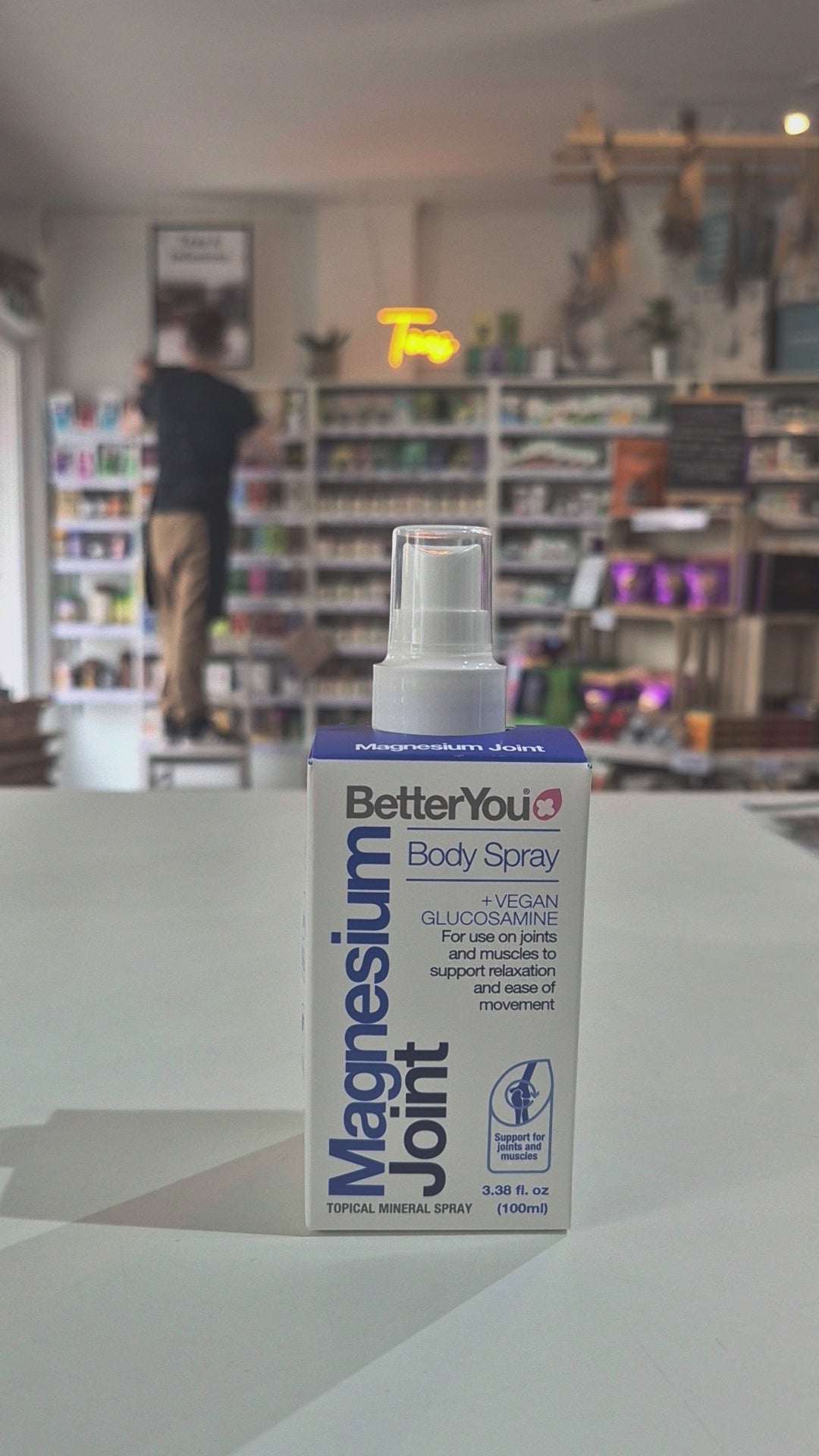 A bottle of Betteryou Magnesium Joint Body Spray with a label showing the brand name, product name, and additional information such as 'vegan', 'glucosamine', and '100ml' video