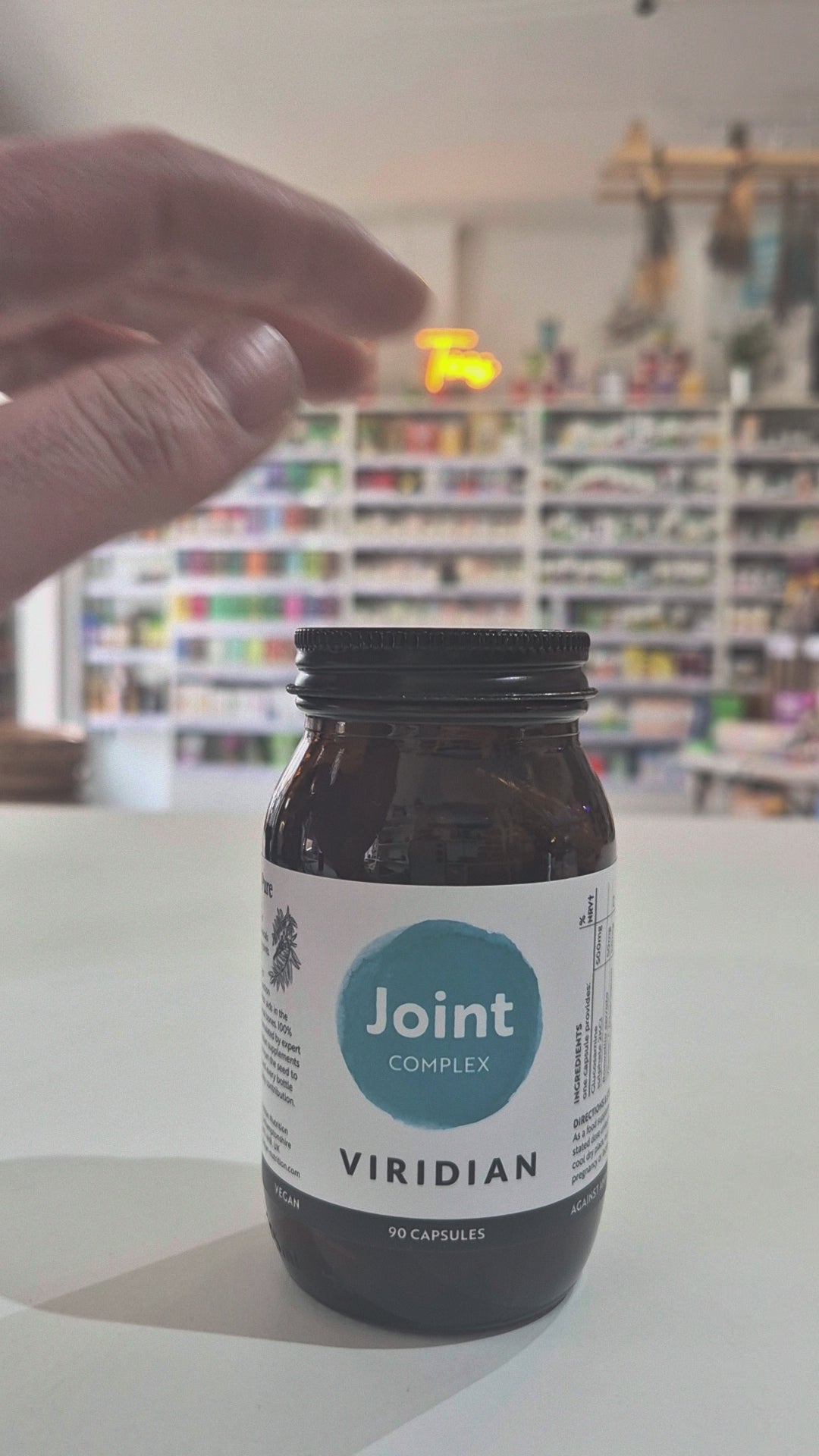 Jar of Viridian Joint Complex on a white surface with a blurred store background