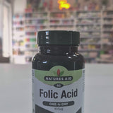 A bottle of Natures Aid Folic Acid supplement with 90 tablets, each providing 400 µg of folic acid. The label indicates the product supports maternal tissue growth during pregnancy and is vegan friendly.