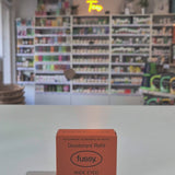 Fussy compostable deodorant refill container and packaging on a table with a blurred store background video