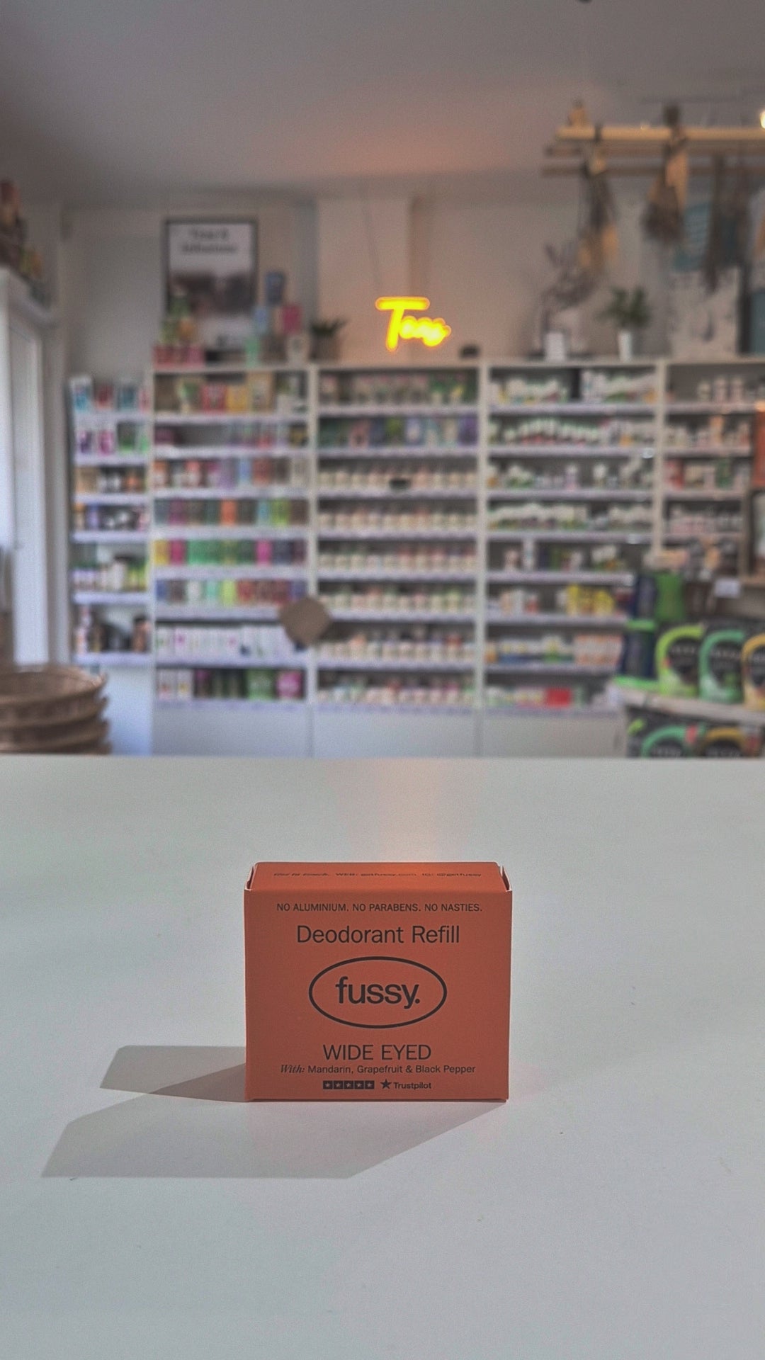 Fussy compostable deodorant refill container and packaging on a table with a blurred store background video
