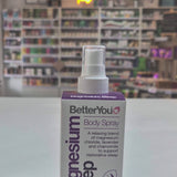 BetterYou Magnesium Sleep body spray bottle on a white surface with a store shelf in the background.