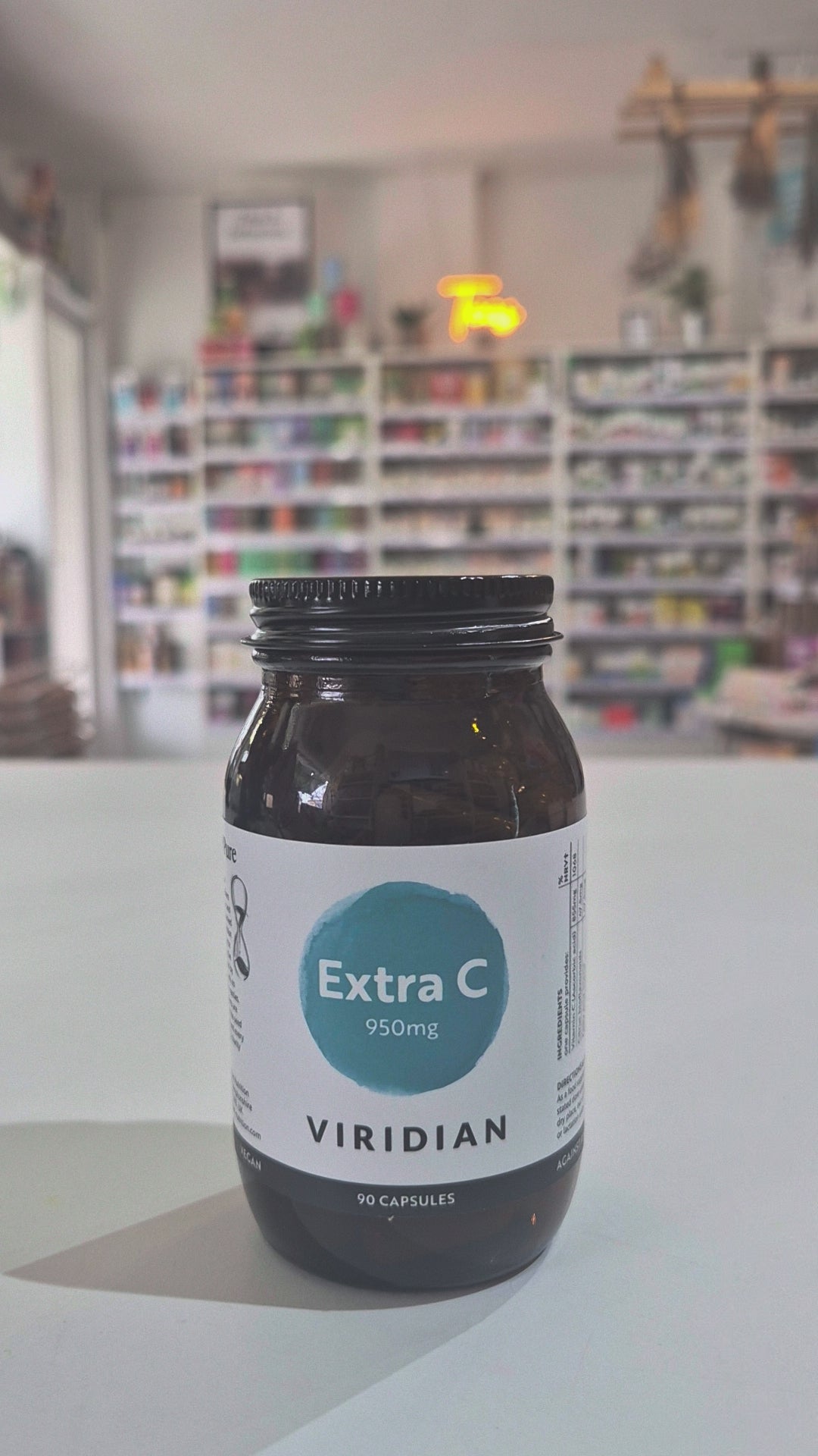 Bottle of Viridian Extra C supplement on a white surface with a blurred background in a shop as a video