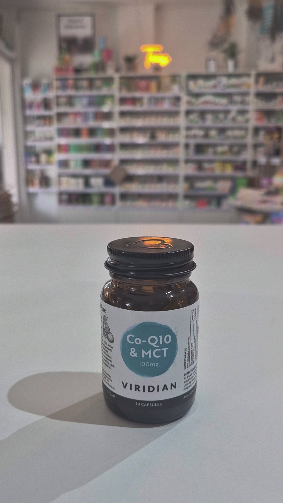 Viridian Co-Q10 & MCT supplement bottle on a white surface with a blurred store background