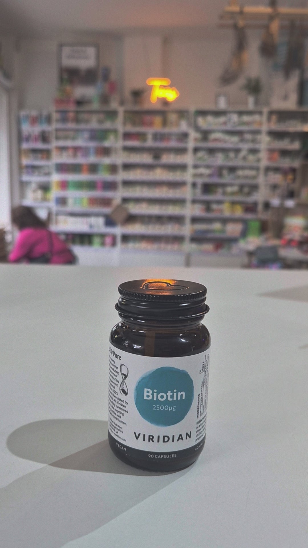 Bottle of Viridian Biotin on a white surface with a blurred store interior in the background video