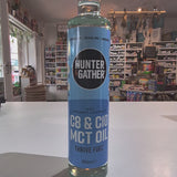 Bottle of Hunter Gatherer MCT oil on a white surface with a blurred store background