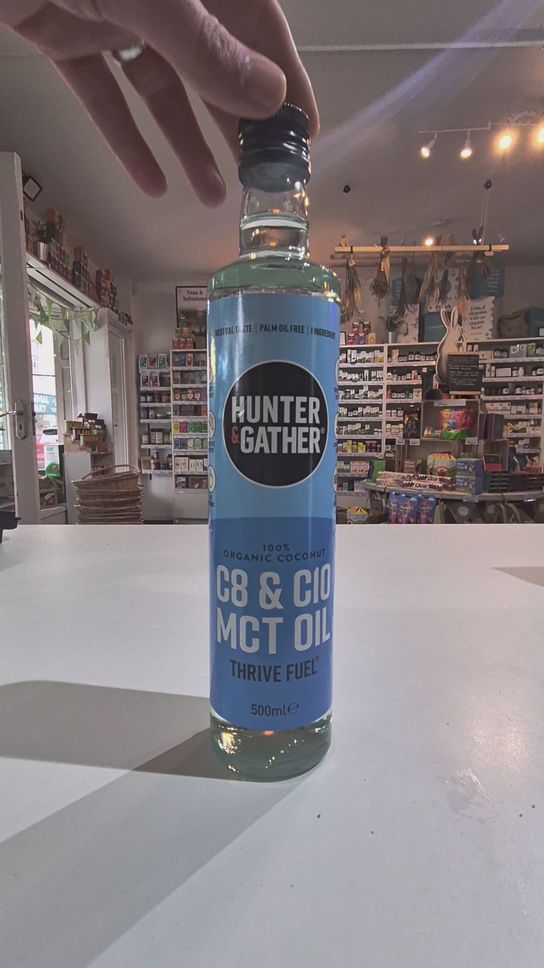 Bottle of Hunter Gatherer MCT oil on a white surface with a blurred store background