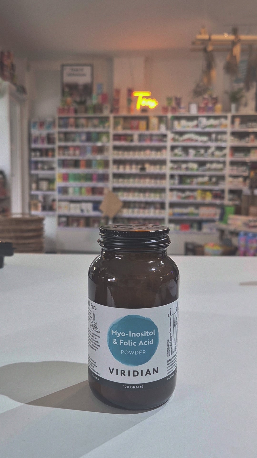 Myo-Inositol & Folic supplement bottle with Viridian label on a white surface, with shop background