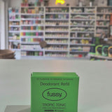 Fussy compostable deodorant refill container and packaging on a counter with a store background.