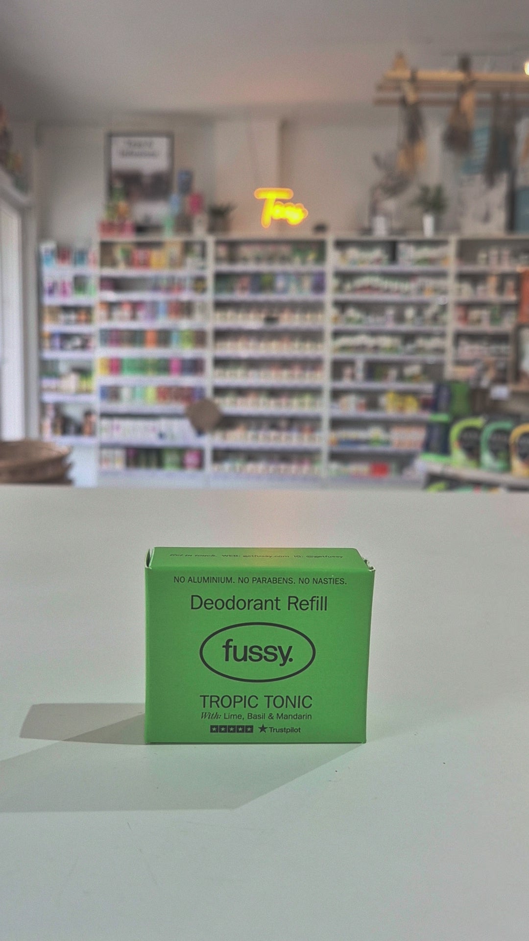 Fussy compostable deodorant refill container and packaging on a counter with a store background.