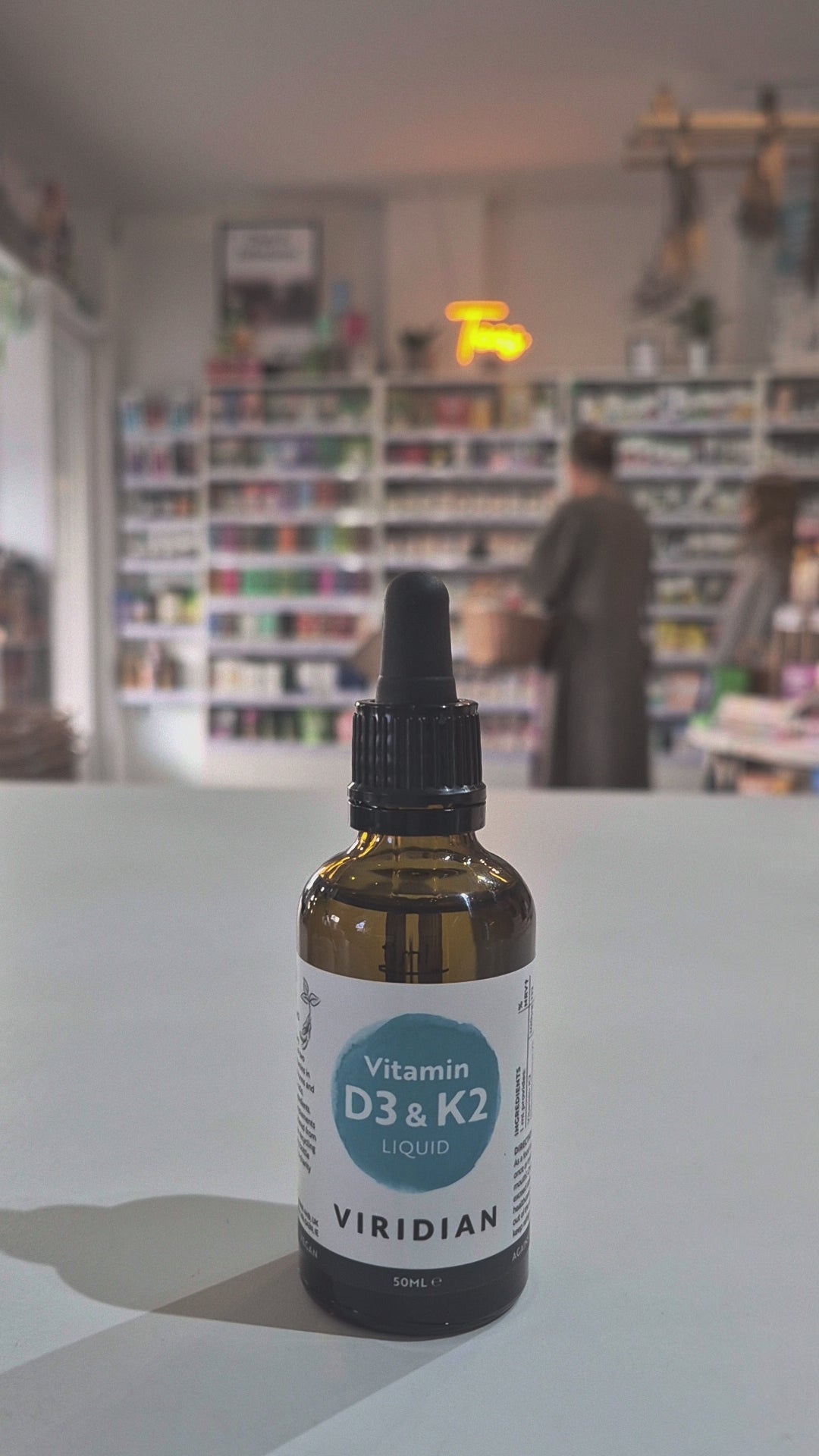 Bottle of Viridian Vitamin D3 & K2 Liquid on a table with a blurred store background as a video. 