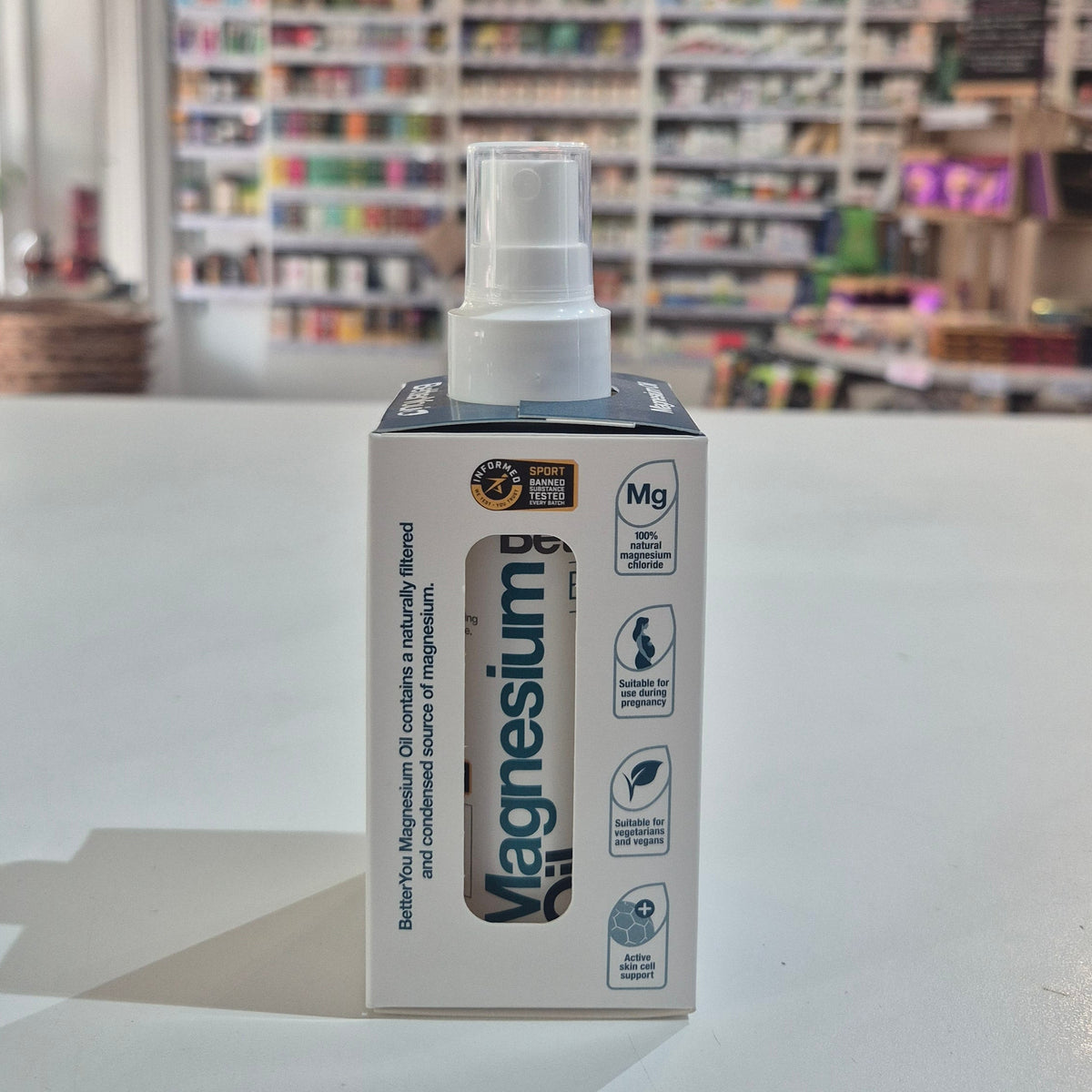 Magnesium oil spray bottle packaging on a table with a blurred store background