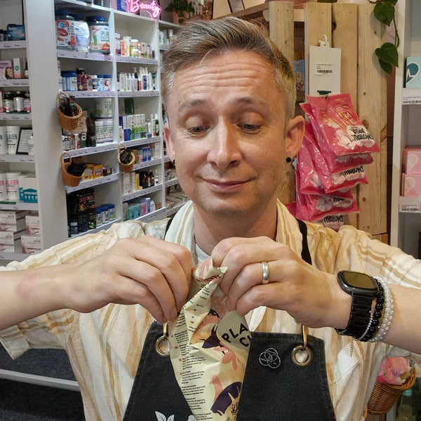Man in a store setting holding a product with shelves and products in the background
