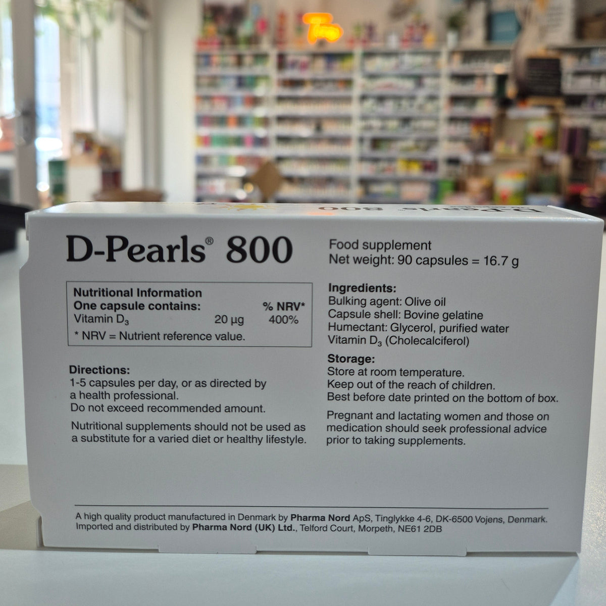 Box of D-Pearls 800 nutritional supplement with blurred store background