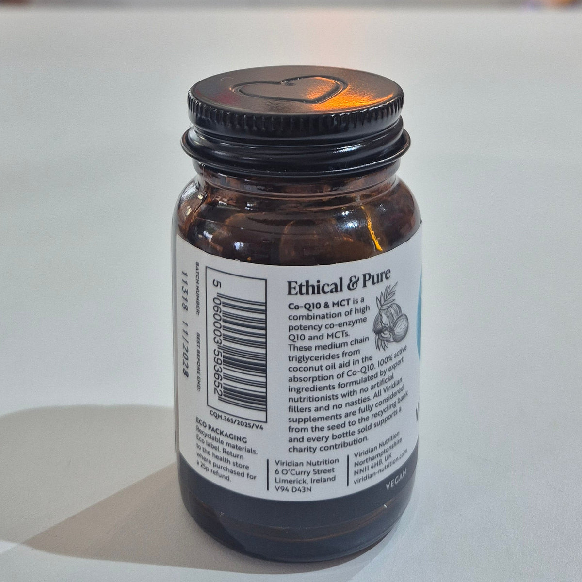 Viridian Co-Q10 & MCT supplement bottle on a white surface with a blurred store background