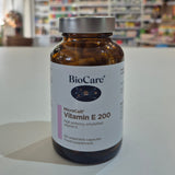BioCare Vitamin E 200 supplement bottle on a table with a blurred background