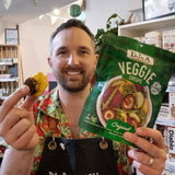 Green package of DJ&A Veggie Crisps with a bowl of colourful vegetables on a white background.