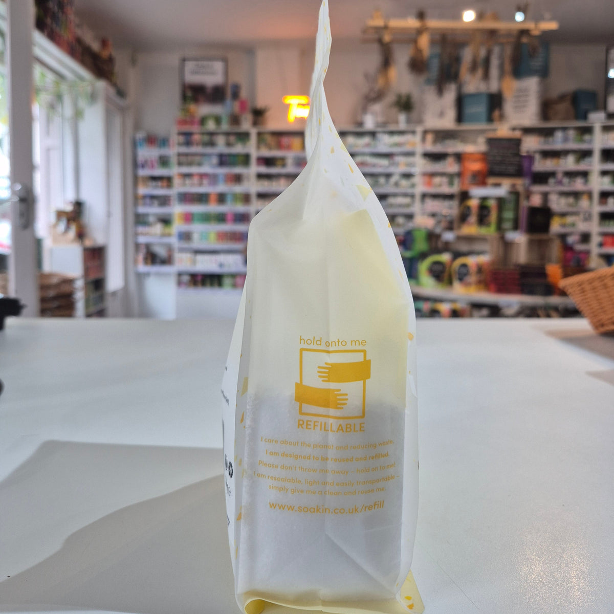 White reusable bag with yellow text on a white surface in a store setting