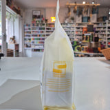 White reusable bag with yellow text on a white surface in a store setting