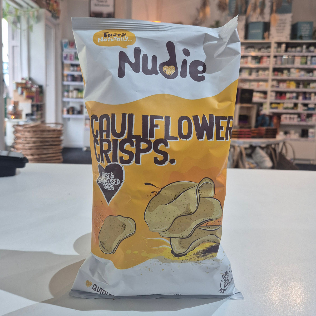 Packaged cauliflower chips cheese and caramelised onion with 'Nudie' branding in a store setting