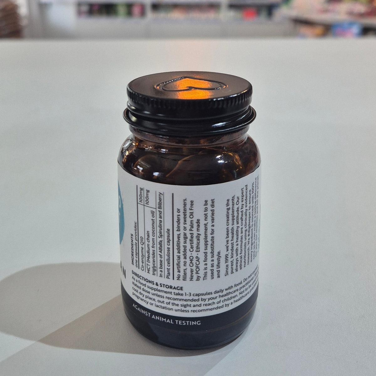 Viridian Co-Q10 & MCT supplement bottle on a white surface with a blurred store background