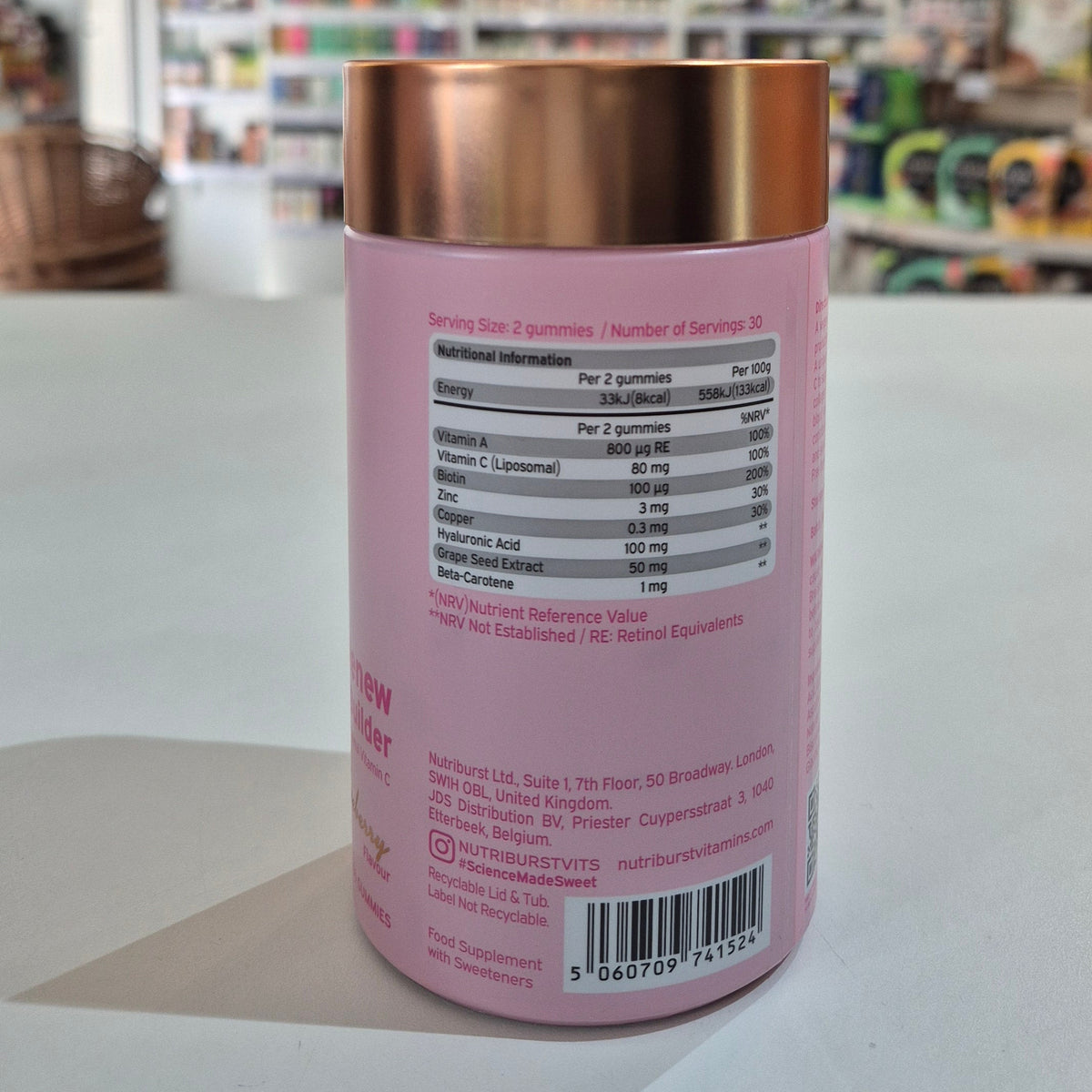 Pink supplement container with a copper lid on a white surface