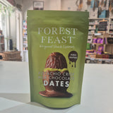 Green package of Forest Feast pistachio crisp milk chocolate dates on a white surface with a store background.