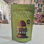 Green package of Forest Feast pistachio crisp milk chocolate dates on a white surface with a store background.