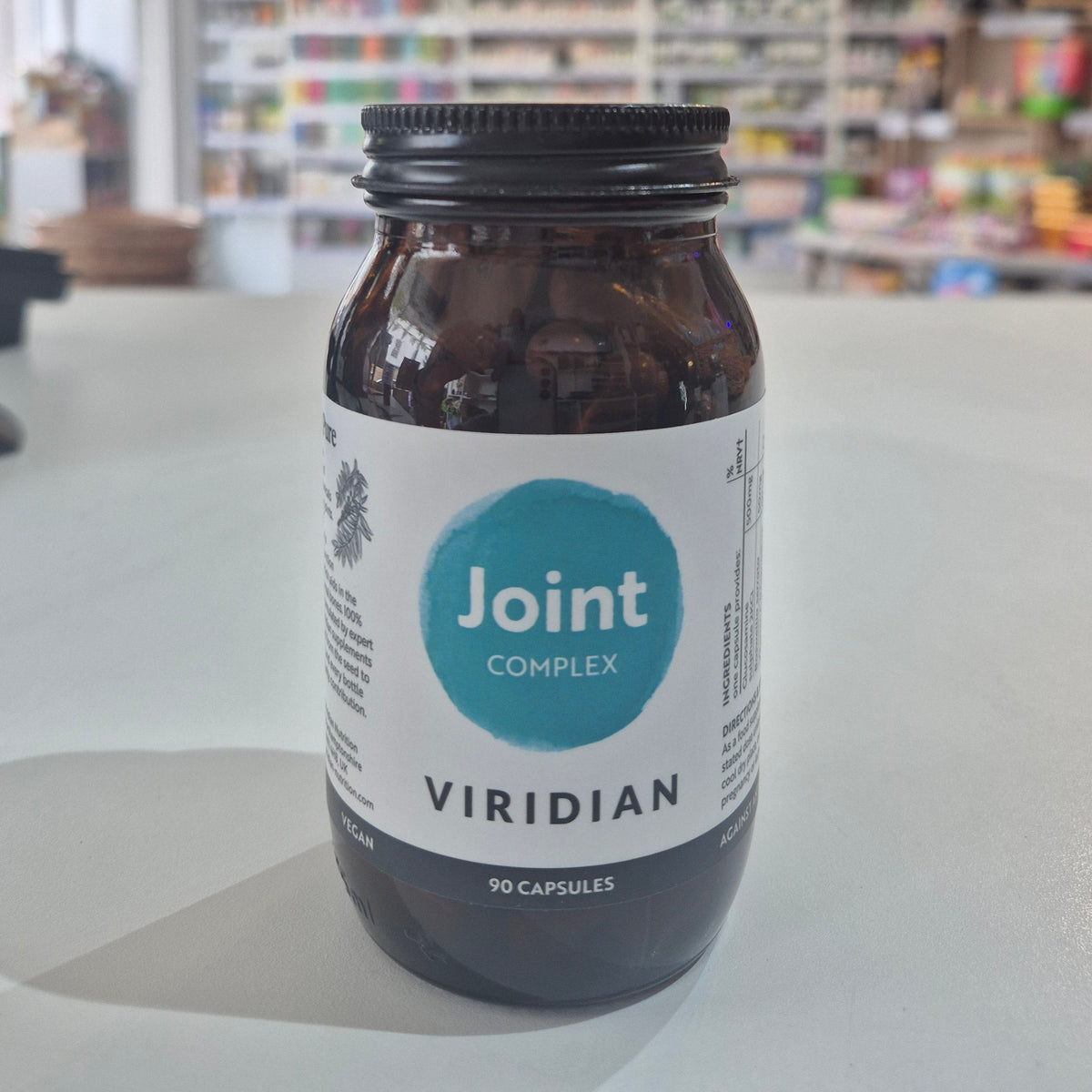 Jar of Viridian Joint Complex on a white surface with a blurred store background