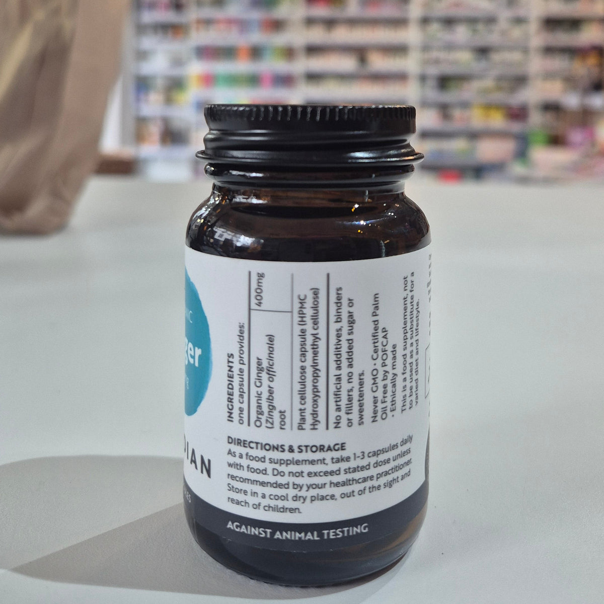 Brown bottle with a label on a white surface, blurred store interior in the background