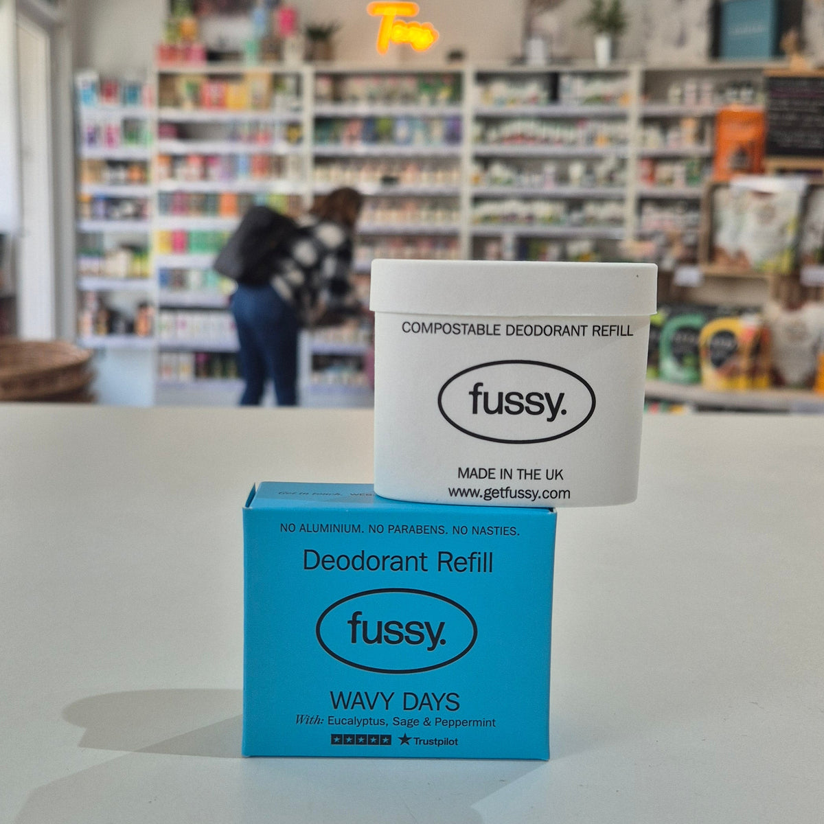 Fussy compostable deodorant refill packaging on a counter with a store background.