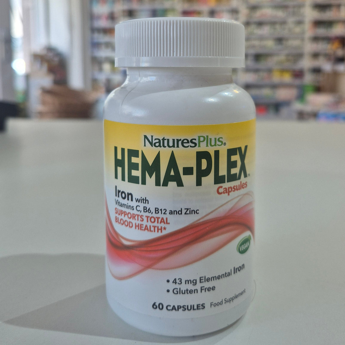 NaturesPlus Hema-Plex supplement bottle on a table with a blurred store background
