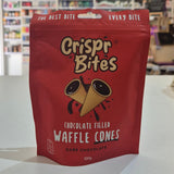 A red stand-up pouch of Crispr Bites Chocolate Filled Waffle Cones placed on a white countertop in a blurred retail shop setting.