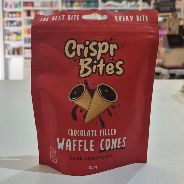 A red stand-up pouch of Crispr Bites Chocolate Filled Waffle Cones placed on a white countertop in a blurred retail shop setting.
