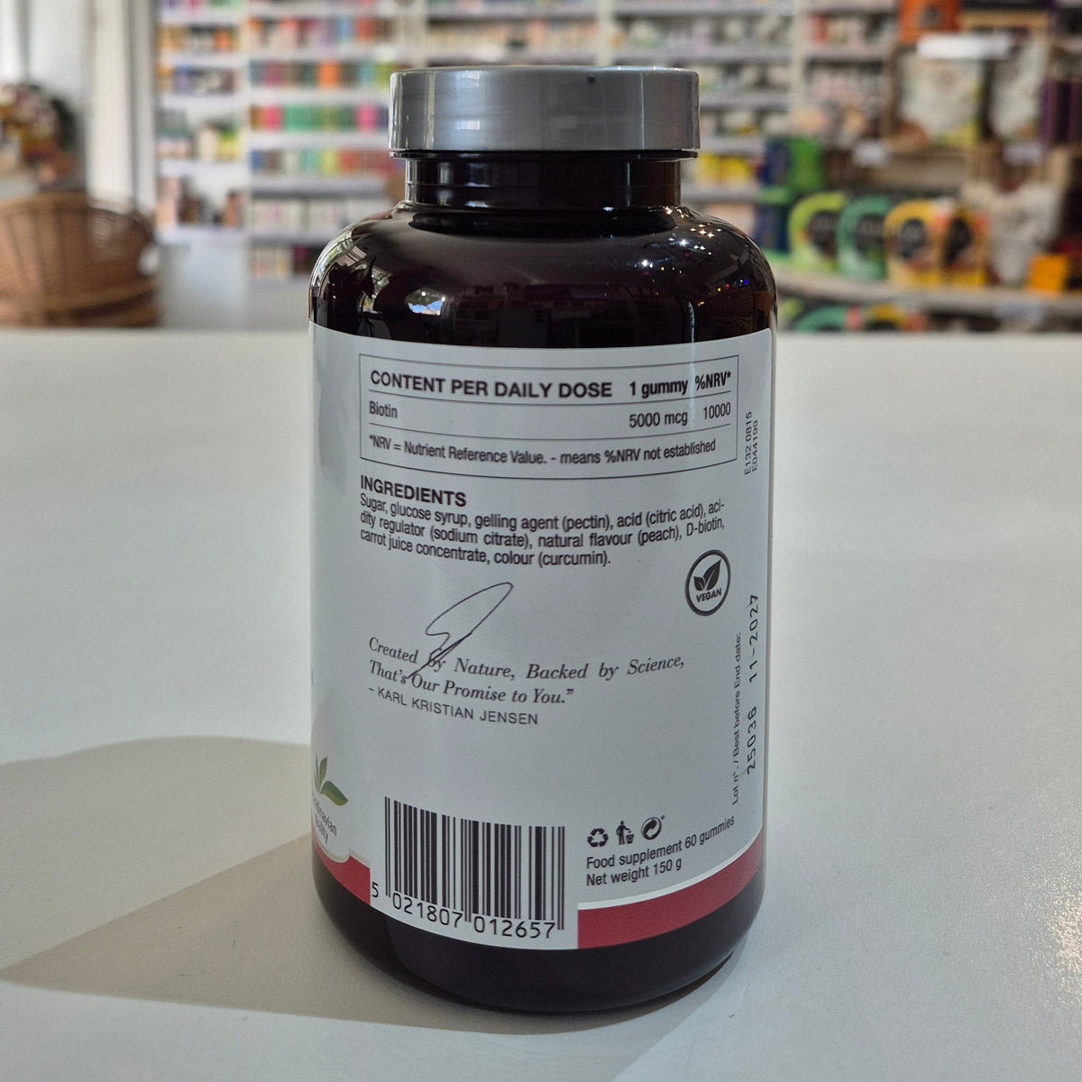 Bottle of New Nordic Biotin Gummies with peach flavor label on a counter. Supplement bottle with label on a counter in a store setting