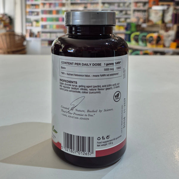 Bottle of New Nordic Biotin Gummies with peach flavor label on a counter. Supplement bottle with label on a counter in a store setting